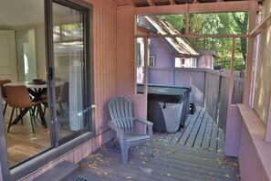 A covered porch with a table and chairs, a covered grill, and a deck with scattered leaves. - NEW! Creekside Lounging. Downtown Manitou Springs. 2 BR/2 BA. A/C. New Hot Tub! (Manitou Springs)