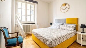 A bedroom with a bed, a chair, a bedside table, a lamp, and a window. - Residenza Pellicceria – Rooftop Terrace in a Historic Palazzo dei Rolli (Genoa)