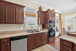 A kitchen with wooden cabinets, a dishwasher, a double sink, and a stove. - Cozy Hunter s Retreat Wraparound Porch Fireplace (Thomson)
