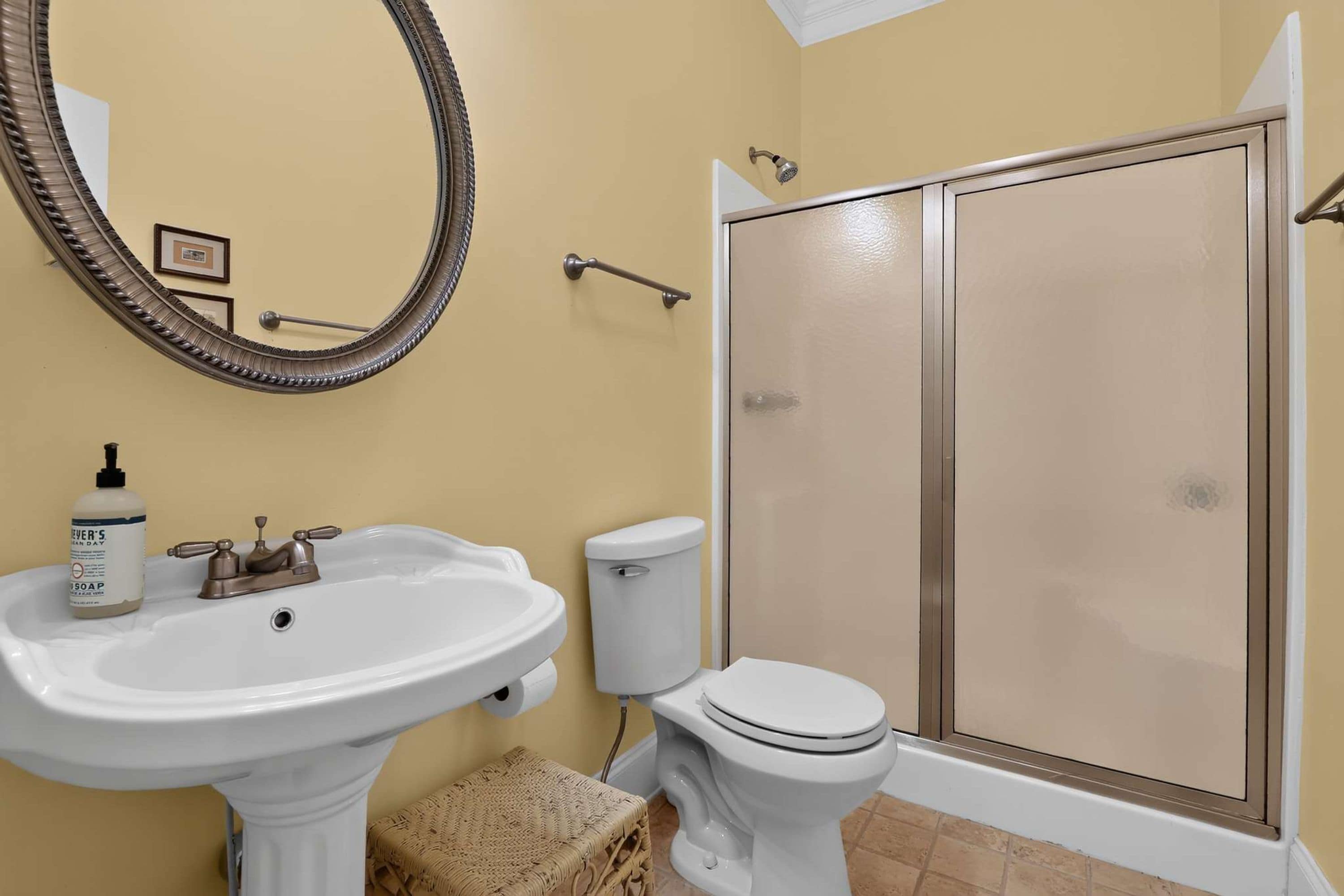 A bathroom with a pedestal sink, toilet, and a walk-in shower with a glass door.