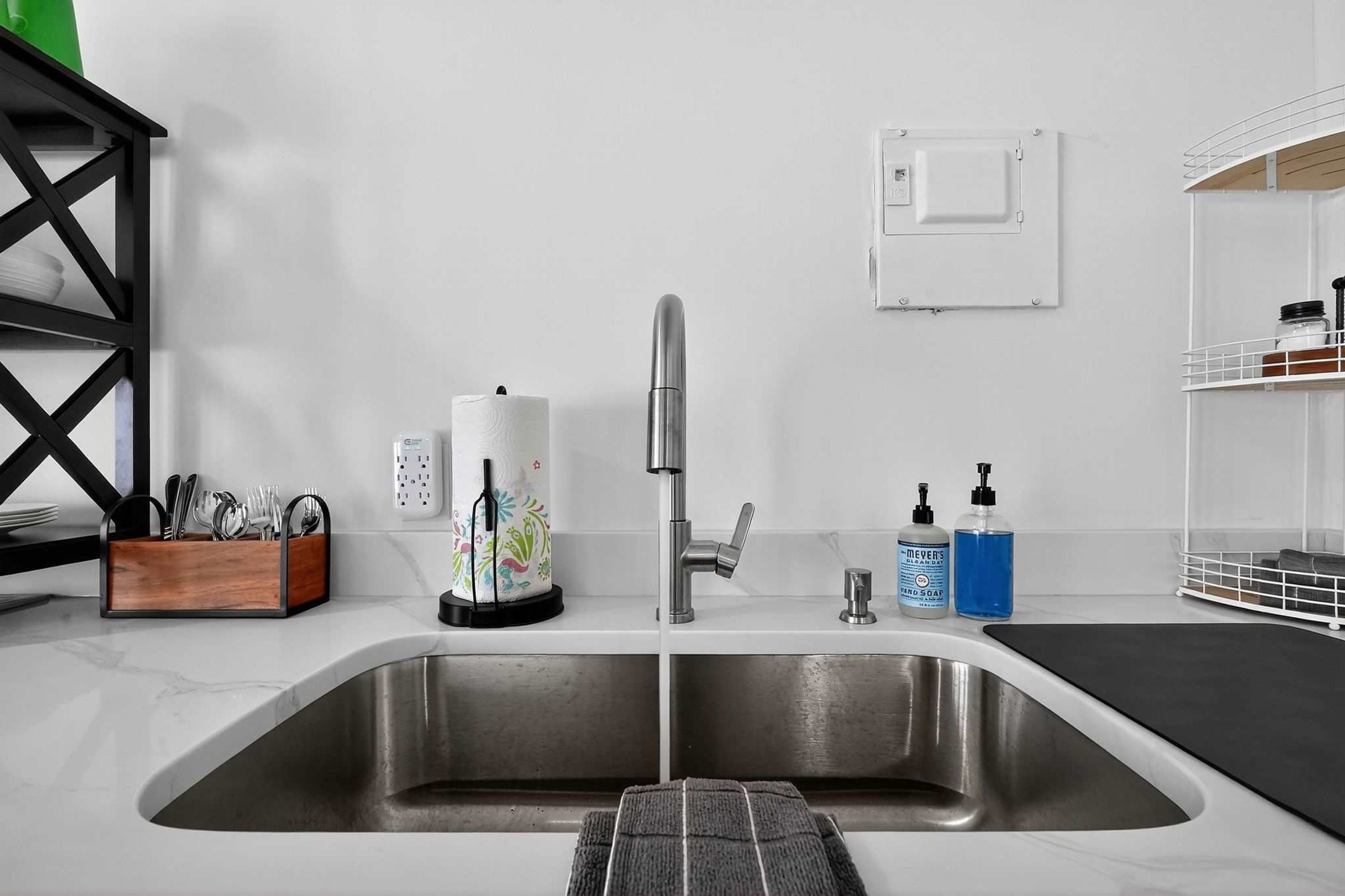 A modern kitchen with a stainless steel sink, a coffee machine, and a soap dispenser.