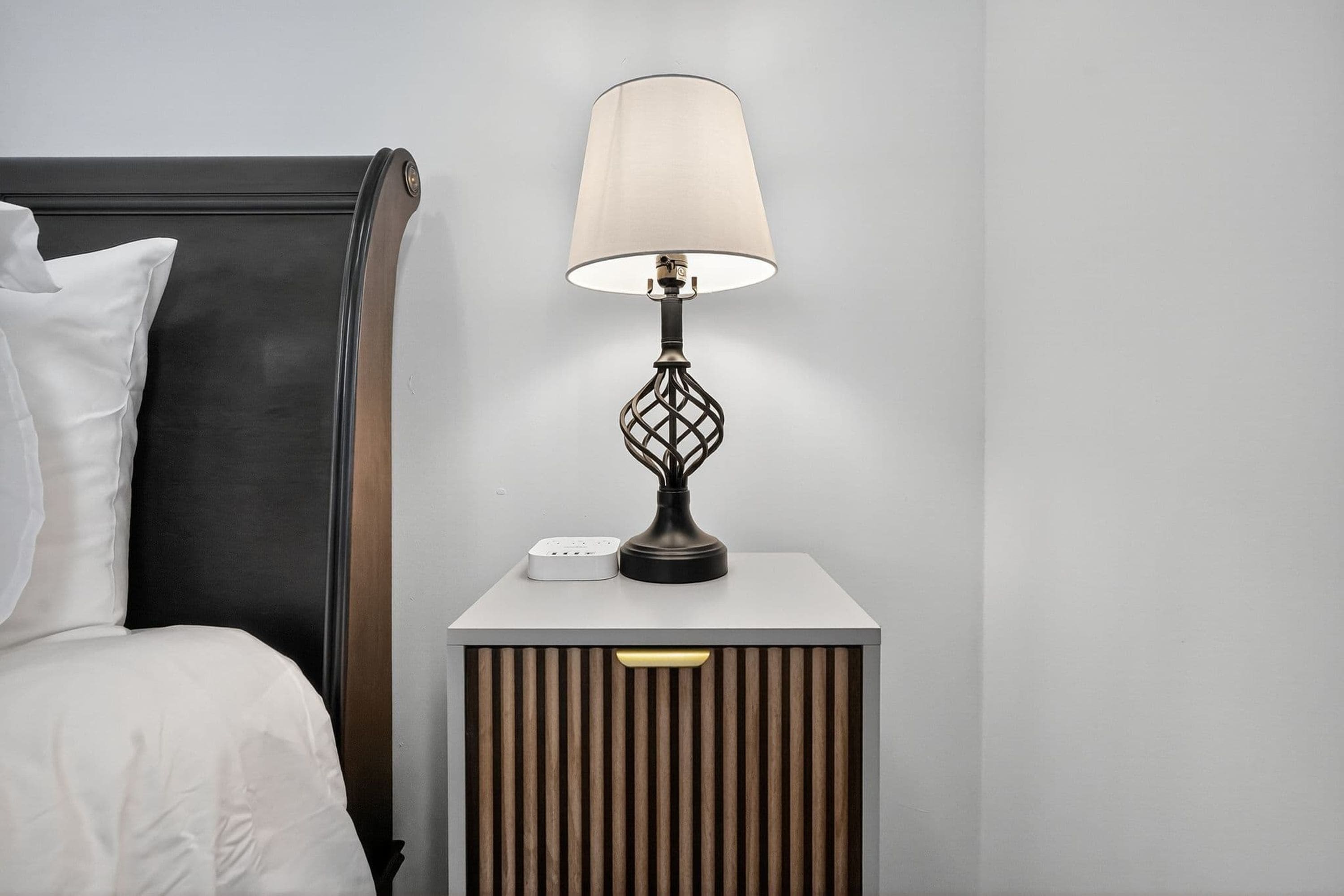 Une chambre d’hôtel avec un lit, une table de chevet avec une lampe et une prise de courant.