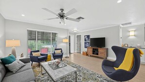 Ein modernes Wohnzimmer mit Deckenventilator, einer Couch, einem Couchtisch und einem Fernseher.