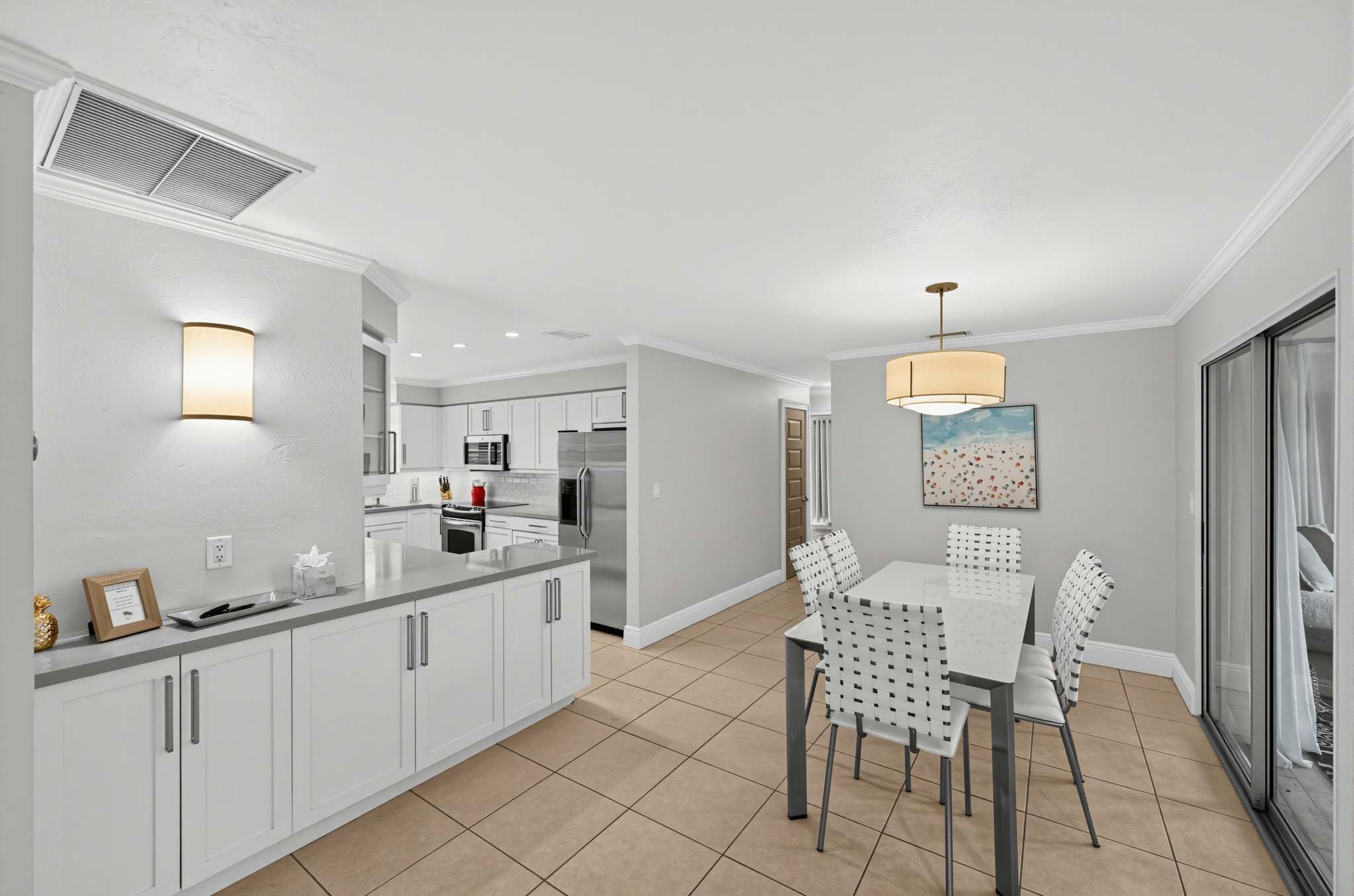 Una cocina moderna con armarios blancos, una isla central y un comedor con mesa y sillas.