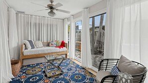 A room with a bed, a chair, a ceiling fan, and a large window. - Coastal Naples Park Getaway - Garden Grill Beach Nearby (Naples)