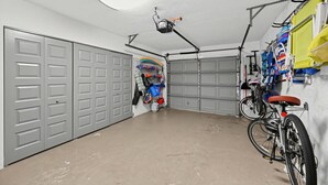 A garage with two grey doors, a ceiling fan, a bicycle, and various items hanging on the wall. - Coastal Naples Park Getaway - Garden Grill Beach Nearby (Naples)