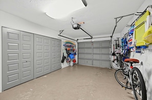 A garage with two grey doors, a ceiling fan, a bicycle, and various items hanging on the wall. - Coastal Naples Park Getaway - Garden Grill Beach Nearby (Naples)