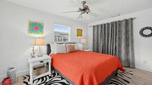 A bedroom with a bed, a ceiling fan, a window, and a view of a building outside. - Coastal Naples Park Getaway - Garden Grill Beach Nearby (Naples)
