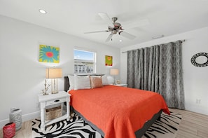 A bedroom with a bed, a ceiling fan, a window, and a view of a building outside. - Coastal Naples Park Getaway - Garden Grill Beach Nearby (Naples)