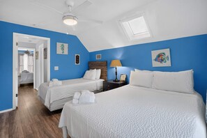 Ein Hotelzimmer mit zwei Betten, einem Deckenventilator, einem Fenster und Bildern an den Wänden.