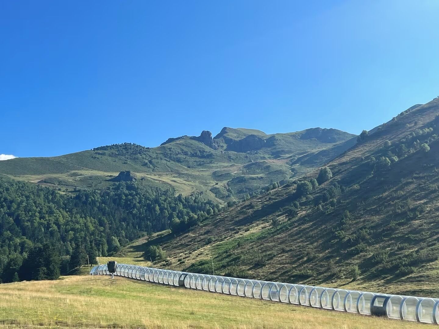Een rij doorzichtige kassen in een heuvelachtig landschap.
