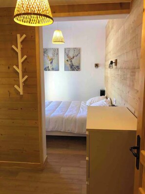 A wooden interior with a bed, a small desk, and a wall-mounted shelf. - Off-Piste | At the Foot of the Slopes in Val Louron (Génos)