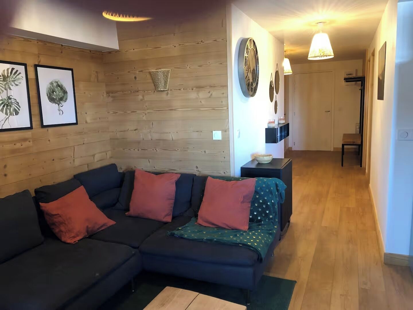 A modern living room with a sectional sofa, a small side table, and a hallway leading to a door.