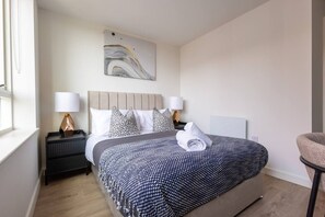 A hotel room with a bed, two bedside lamps, a painting on the wall, and a chair. - Birmingham City Retreat No 145 (Birmingham)