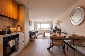 A modern kitchen with a dining area, wooden cabinets, and a large window. - Birmingham City Retreat No 145 (Birmingham)