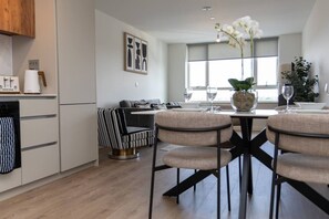 A modern kitchen with a dining area, featuring a striped sofa, a table with chairs, and a vase with flowers. - Birmingham City Retreat No 145 (Birmingham)