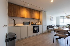 A modern kitchen with a built-in oven, microwave, and sink. There is a dining area with a table and chairs. - Birmingham City Retreat No 145 (Birmingham)