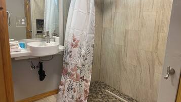 A bathroom with a shower, a sink, and a mirror.