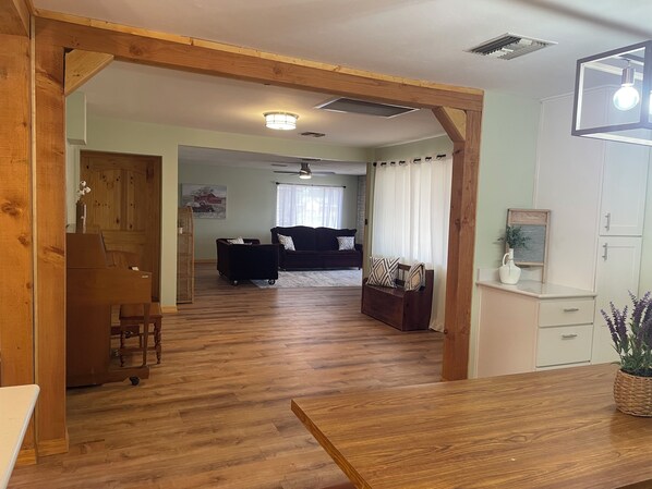 A living room with a wooden floor, a sofa, a coffee table, and a dining table.