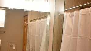 Een badkamer met een wastafel, spiegel en douchegordijn.