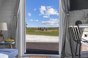 Una habitación con un amplio ventanal que ofrece vistas a un campo verde y un cielo despejado.