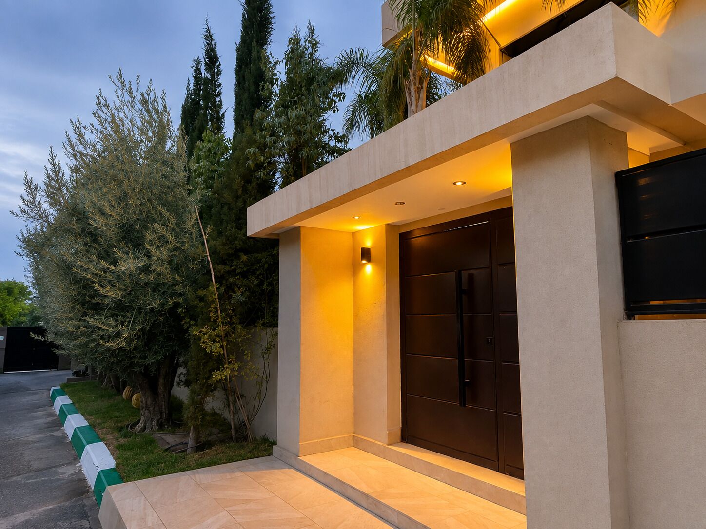 A modern building with a large entrance, a well-lit exterior, and a paved driveway.