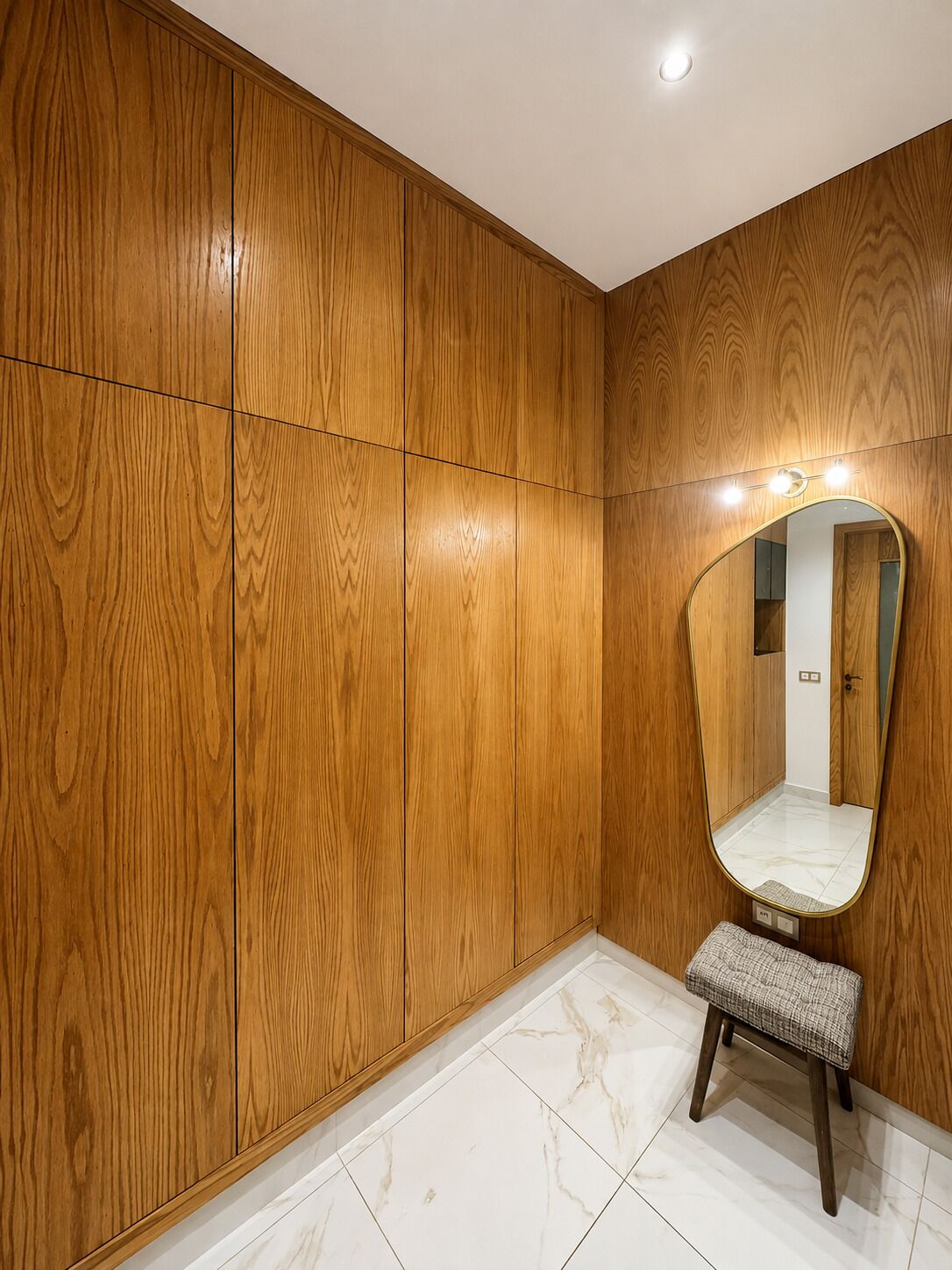 A wooden wardrobe with a mirror and a bench.