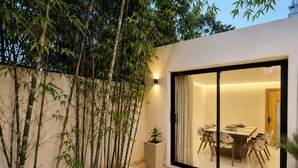 A modern outdoor dining area with a glass door leading to a room, surrounded by bamboo plants. - PREMIUM EXPERIENCE - MODERN VILLA WITH EXCEPTIONAL COMFORT (مراكش)