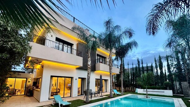 A modern two-story house with a swimming pool, outdoor furniture, and a well-maintained garden. - PREMIUM EXPERIENCE - MODERN VILLA WITH EXCEPTIONAL COMFORT (مراكش)