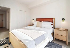 Een hotelkamer met een bed, nachtkastjes en een deur.