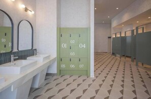 Ein modernes Badezimmer mit mehreren Waschbecken, einem grünen Spindenbereich und einem gemusterten Boden.