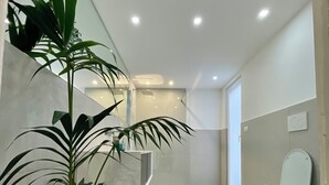 Un baño moderno con inodoro, bidé y una planta en maceta.