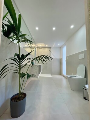 Une salle de bain moderne avec des toilettes, un bidet et une plante en pot.