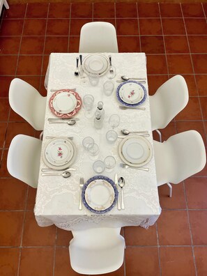 A dining table set with white chairs, plates, cutlery, and glasses. - Fil's House—located in the historic district, close from the botanical garden (Catania)