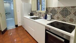 Una cocina con armarios blancos, salpicadero de azulejos, estufa y lavamanos.
