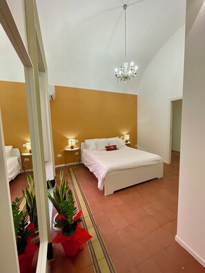 Une chambre à coucher avec un lit, des tables de chevet, un lustre et des plantes en pot.
