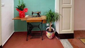 Habitación en esquina con pared color turquesa, una mesa de madera con una máquina de coser, una planta en maceta y una puerta blanca.