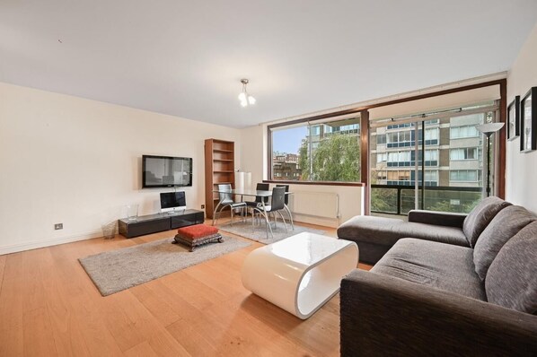 En moderne stue med sofa, sofabord, fjernsyn og spiseplads med stole og bord.