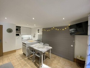 A compact kitchen with a dining table, white cabinets, and a grey wall with string lights. - 150m from ski slopes, 2nd floor, balcony, tv, ski locker, 47m², Montchavin La Plagne (Bellentre)