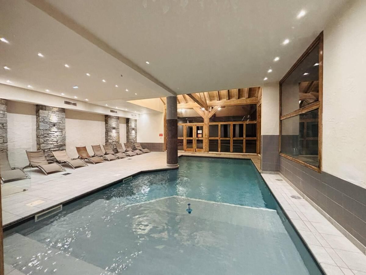 Piscina interna com espreguiçadeiras e parede de pedra.