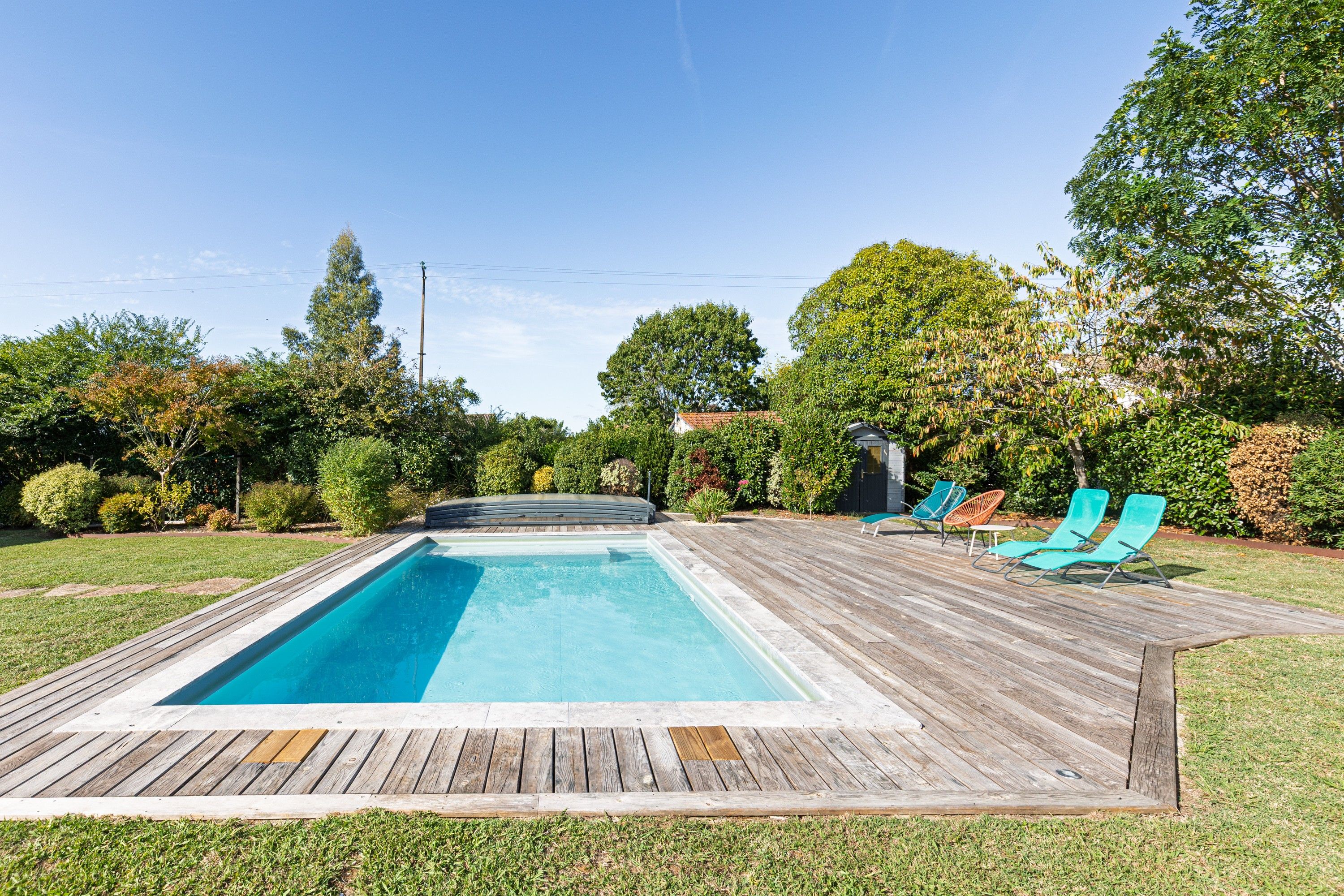 Una piscina rectangular amb una terrassa de fusta al voltant.