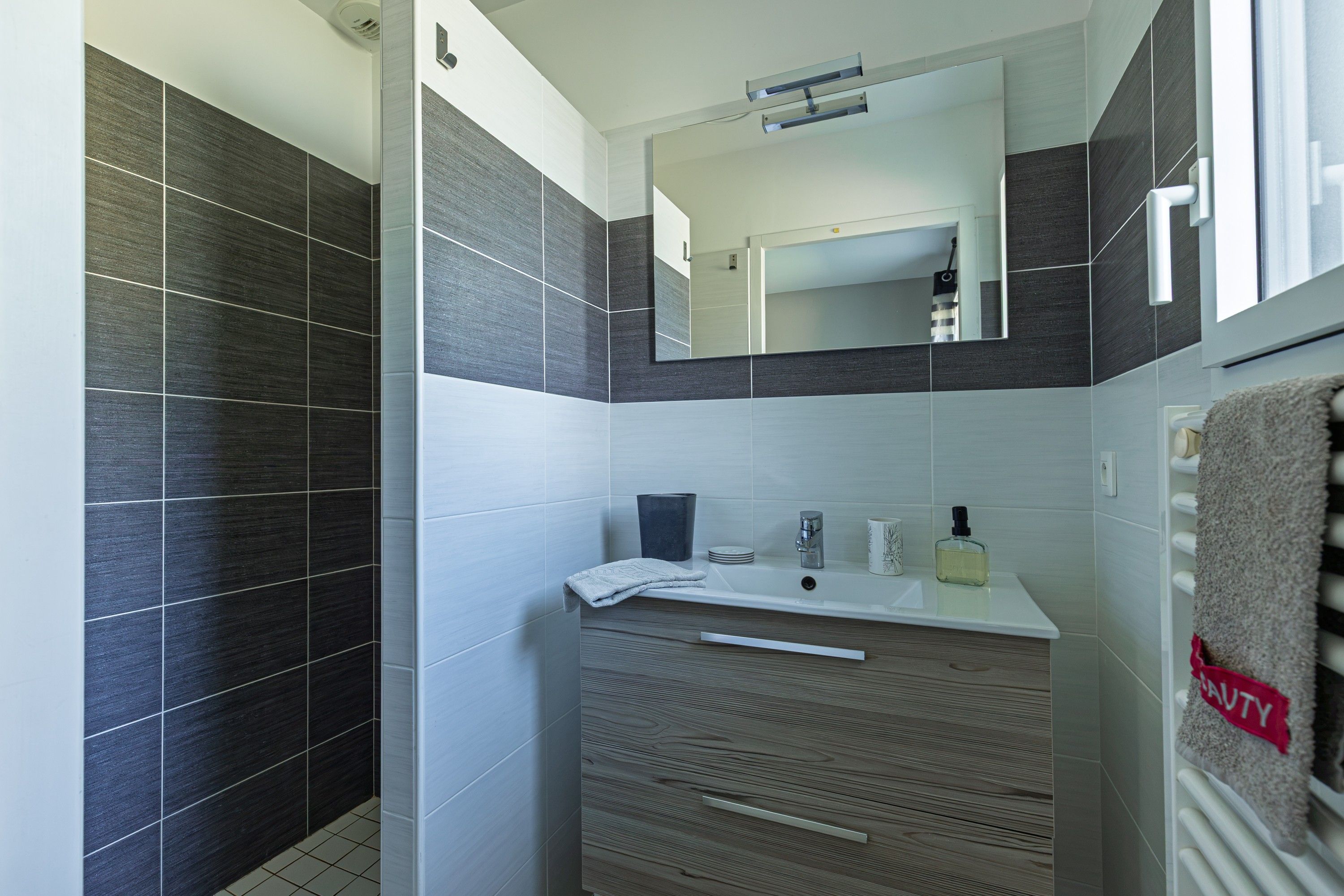 Un bagno moderno con doccia, lavandino e specchio.