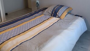 A bedroom with a large bed, a hanging light fixture, and a wall-mounted lamp.