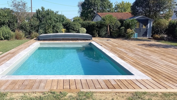 A rectangular swimming pool with a wooden deck surrounding it.
