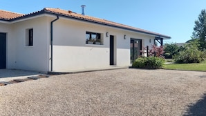 A single-story building with a gravel driveway, a garage door, and a small entrance door.