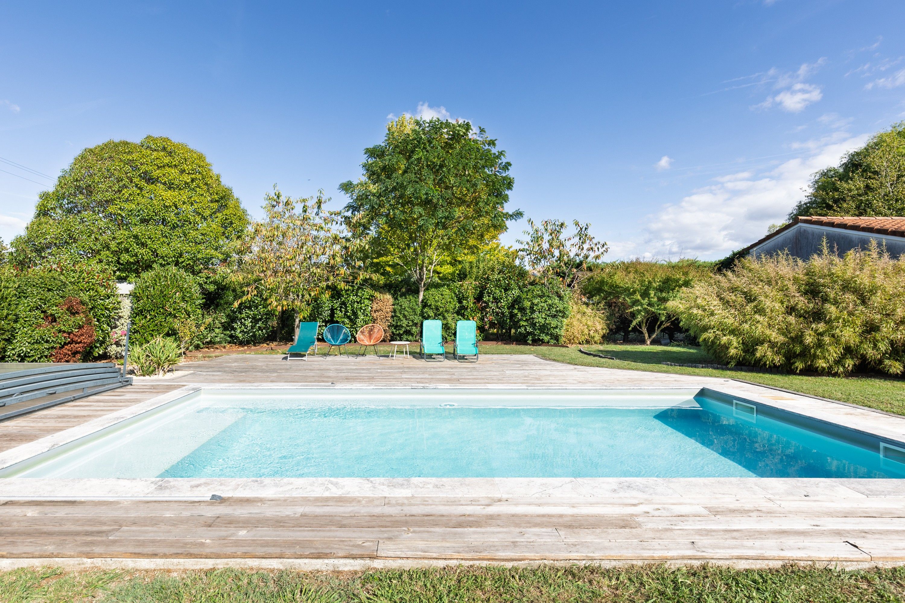 A rectangular swimming pool with a wooden deck in the foreground.
