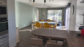 A modern kitchen with built-in appliances, a dining area with a table and chairs, and a view of the outdoors.