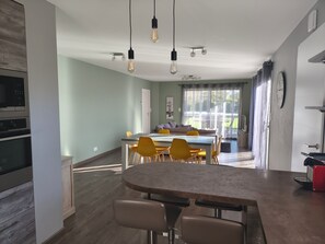 A modern kitchen with built-in appliances, a dining area with a table and chairs, and a view of the outdoors. - Holiday Home “La Maison de Pascale” with Private Pool, Wi-Fi & Air Conditioning (Orist)