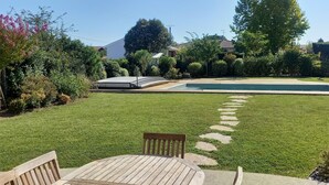 A backyard with a swimming pool, a wooden deck, and a lawn.