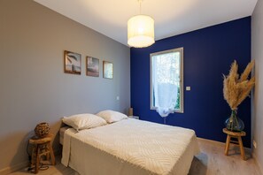 A bedroom with a bed, a window, and a wall with three framed pictures.